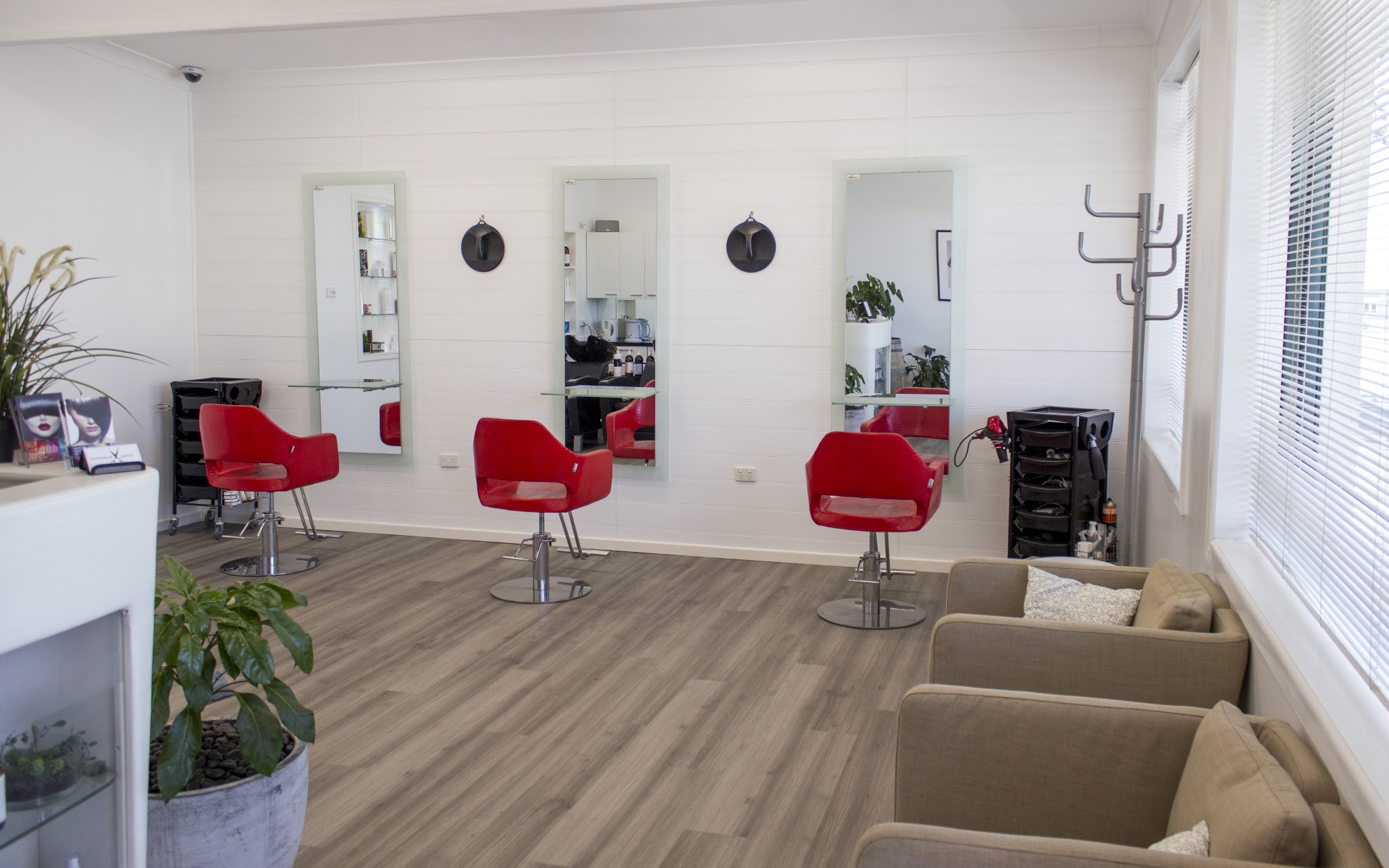 The styling floor at Connie Janz Hair Studio: white shiplap walls, three red chairs and tall mirrors
