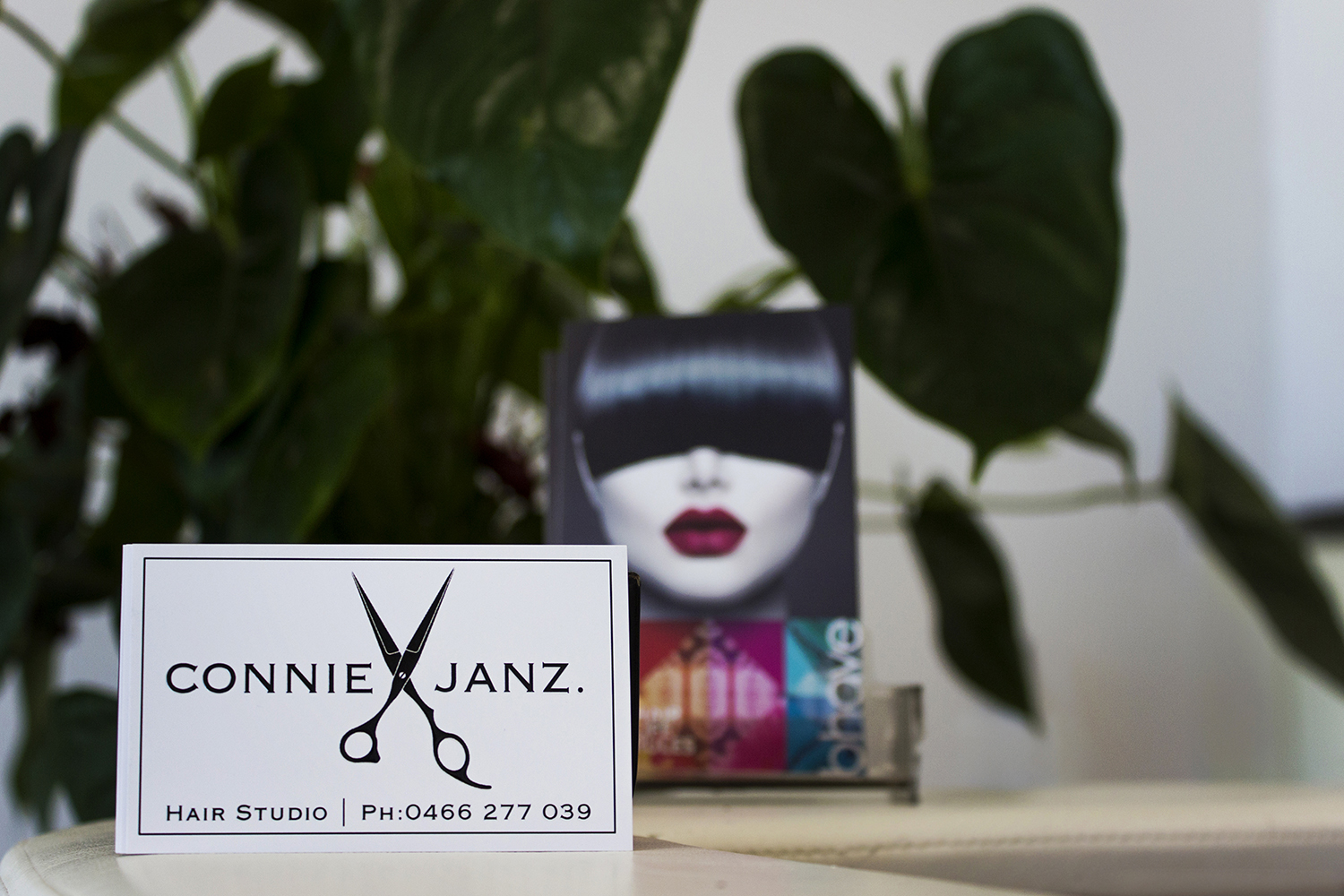 A Connie Janz business card with the scissors logo